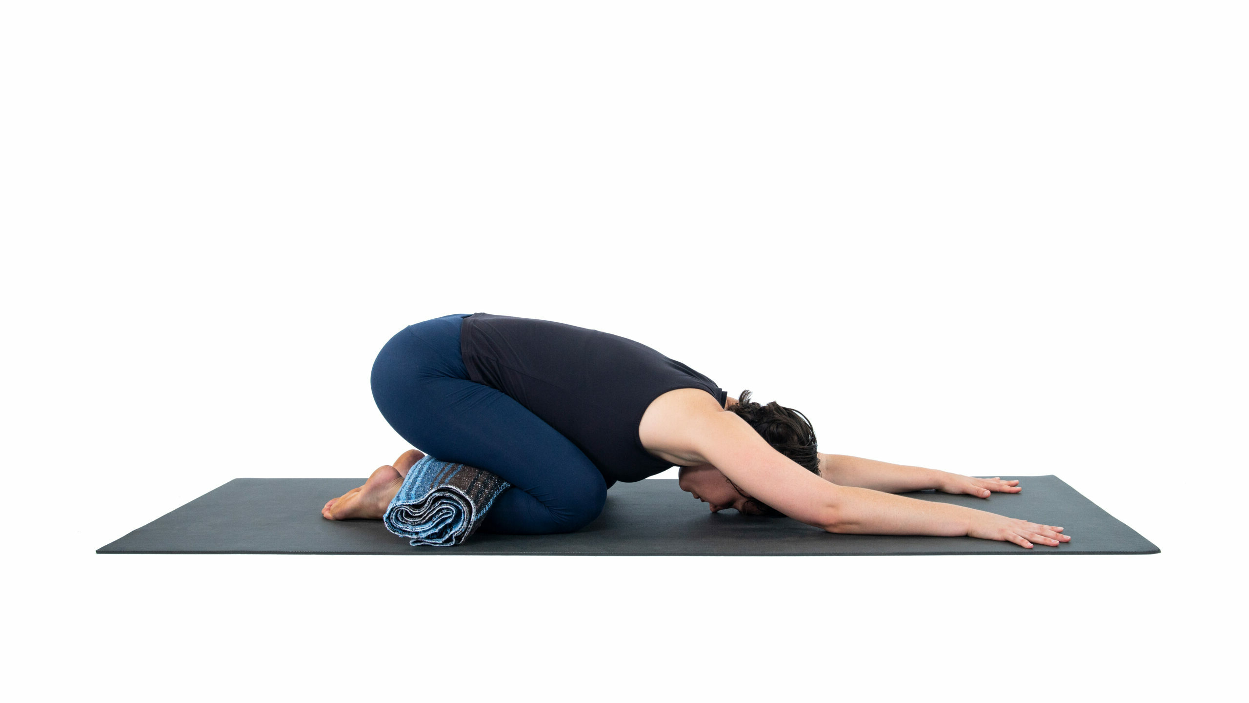 Sporty woman practicing Chid's pose (Balasana) with props to relax your pelvic floor.
