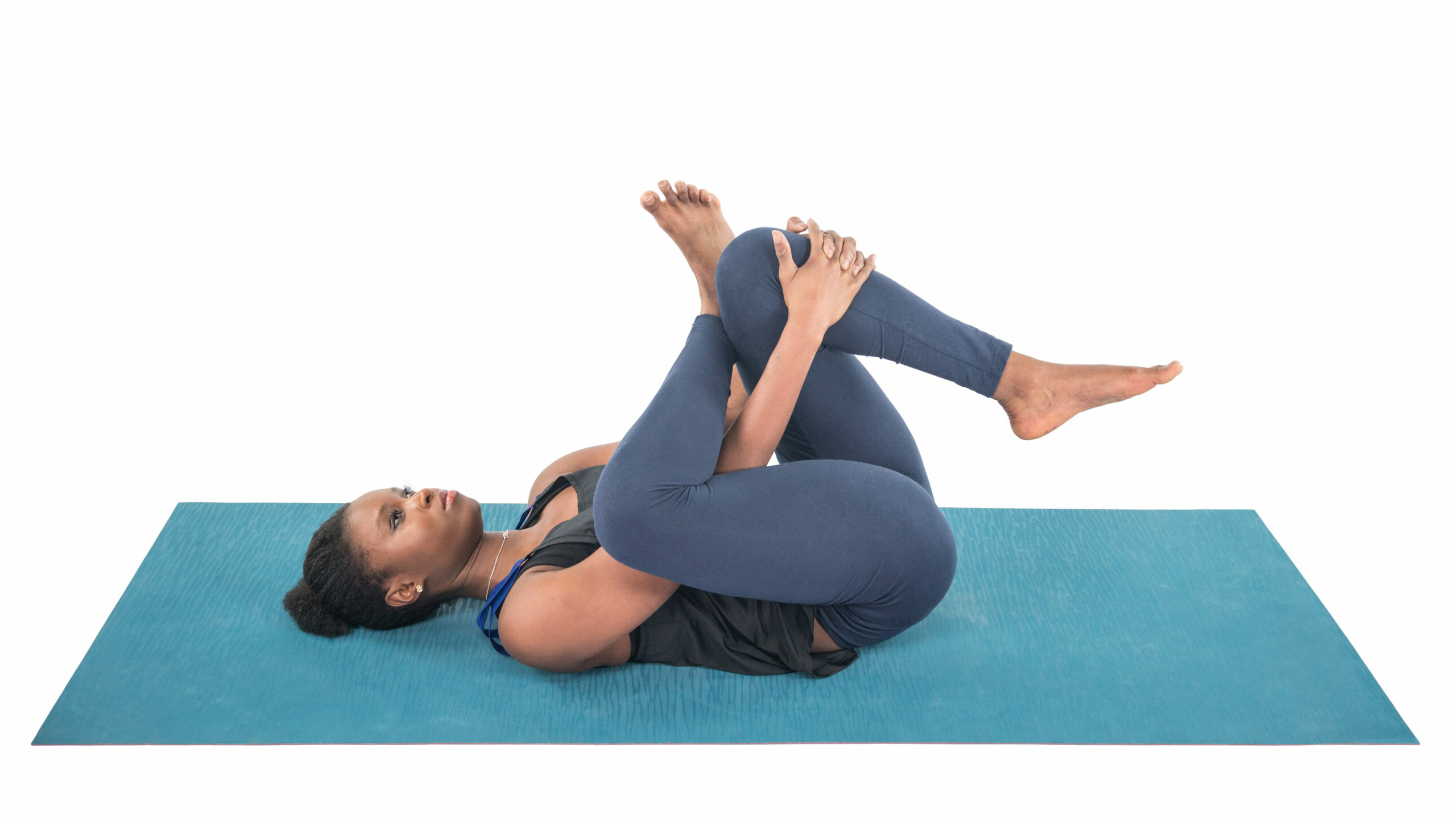 A beautiful black woman practicing reclining pigeon pose (supta kapotasana) a yoga pose for the pelvic floor.