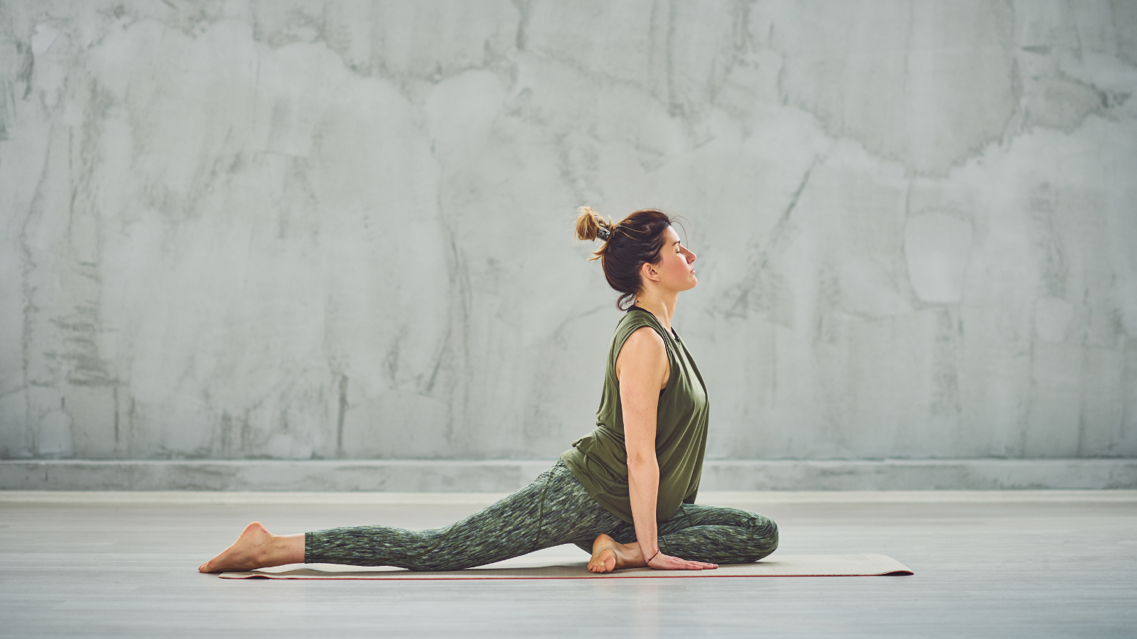 Brunette yogi doing Half Pigeon yoga pose a hip opening and not recommended for all bodies pose