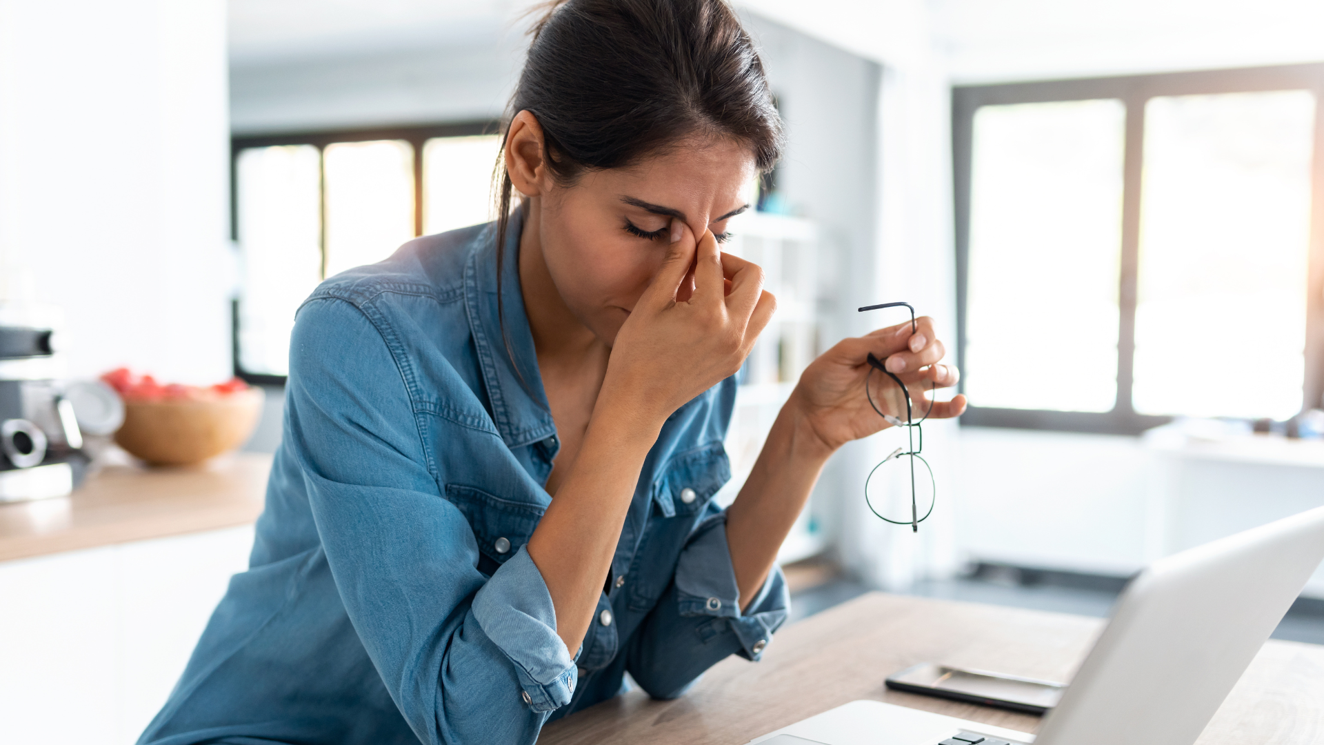 Image of stressed business woman working from home on laptop looking worried, tired and overwhelmed.