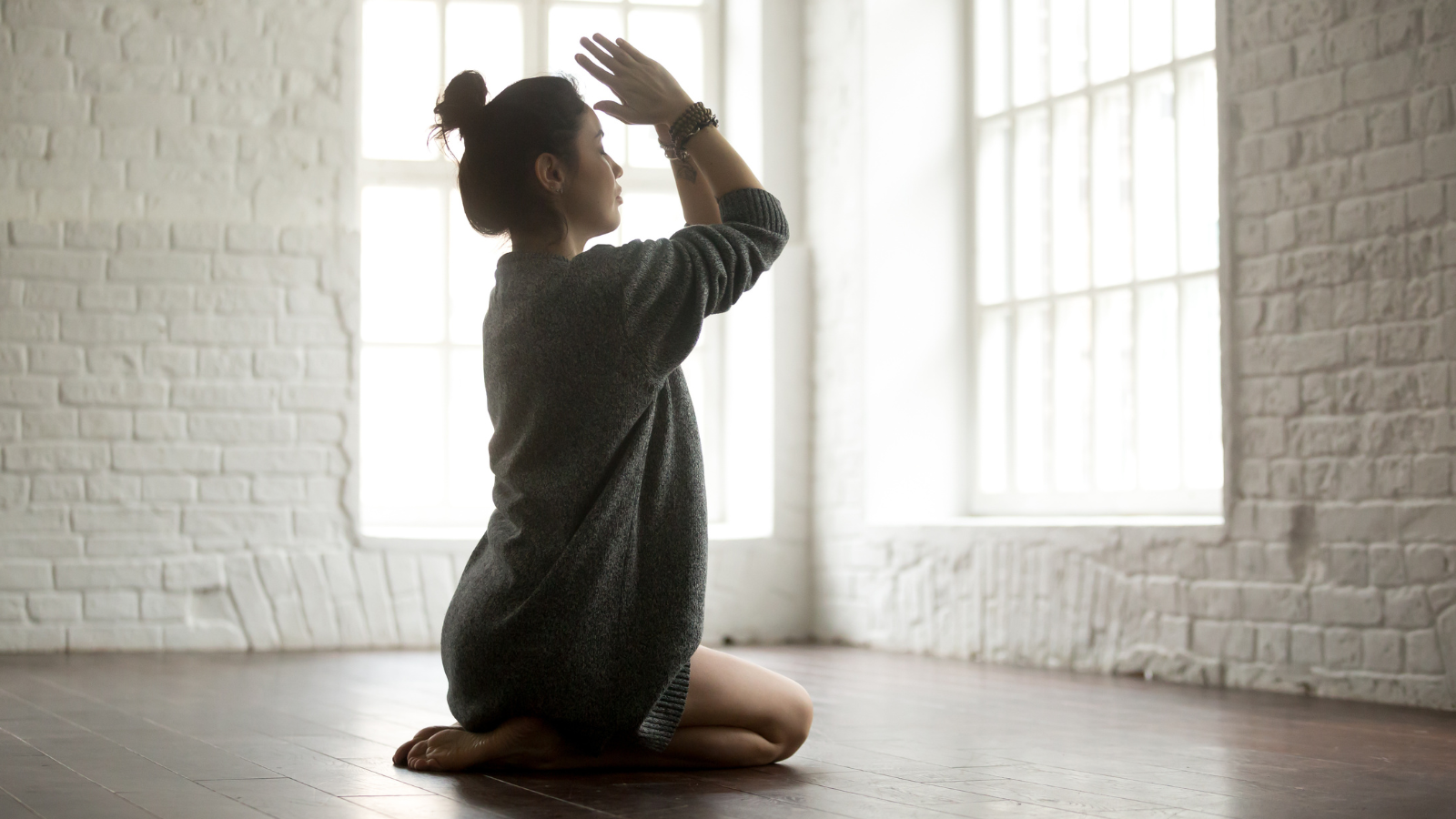 Young attractive yogi woman practicing yoga, sitting in Vajrasana Pose.