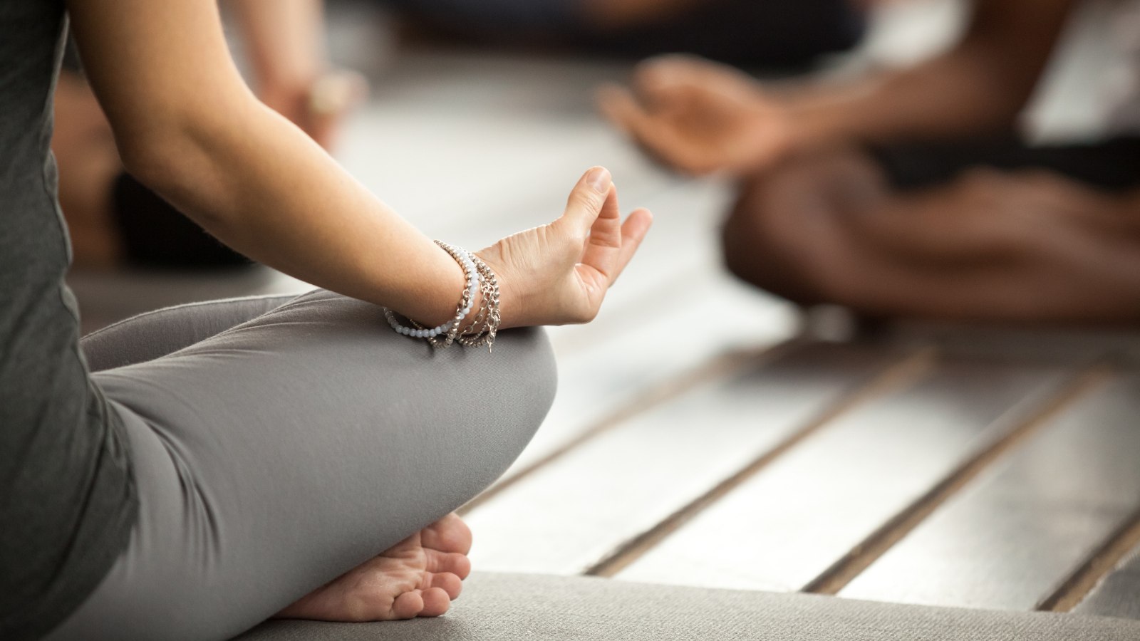 Young sporty woman practicing yoga lesson sitting in Sukhasana or Easy Sitting Pose also practicing with a mudra gesture