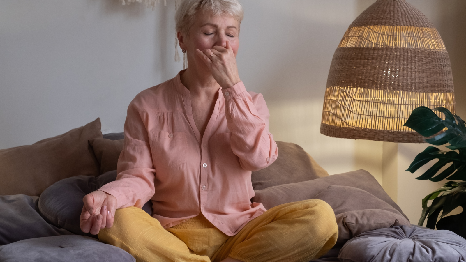 Senior woman practicing Alternate Nostril Breathing exercise, Nadi Shodhana Pranayama at home.